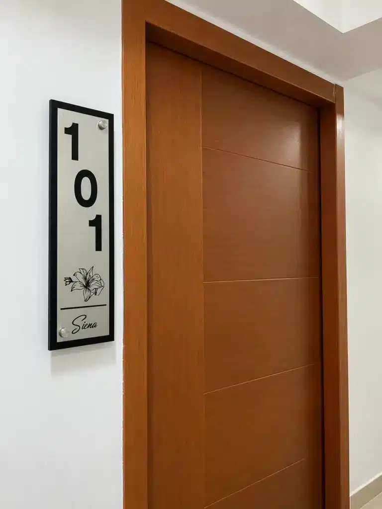 Letrero vertical negro con número 101 junto a una puerta de madera
