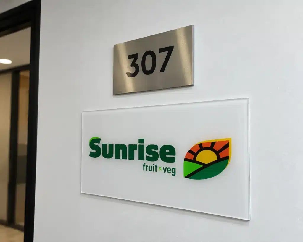 Placa dorada con número 307 y letrero de acrílico con logo en pared de pasillo